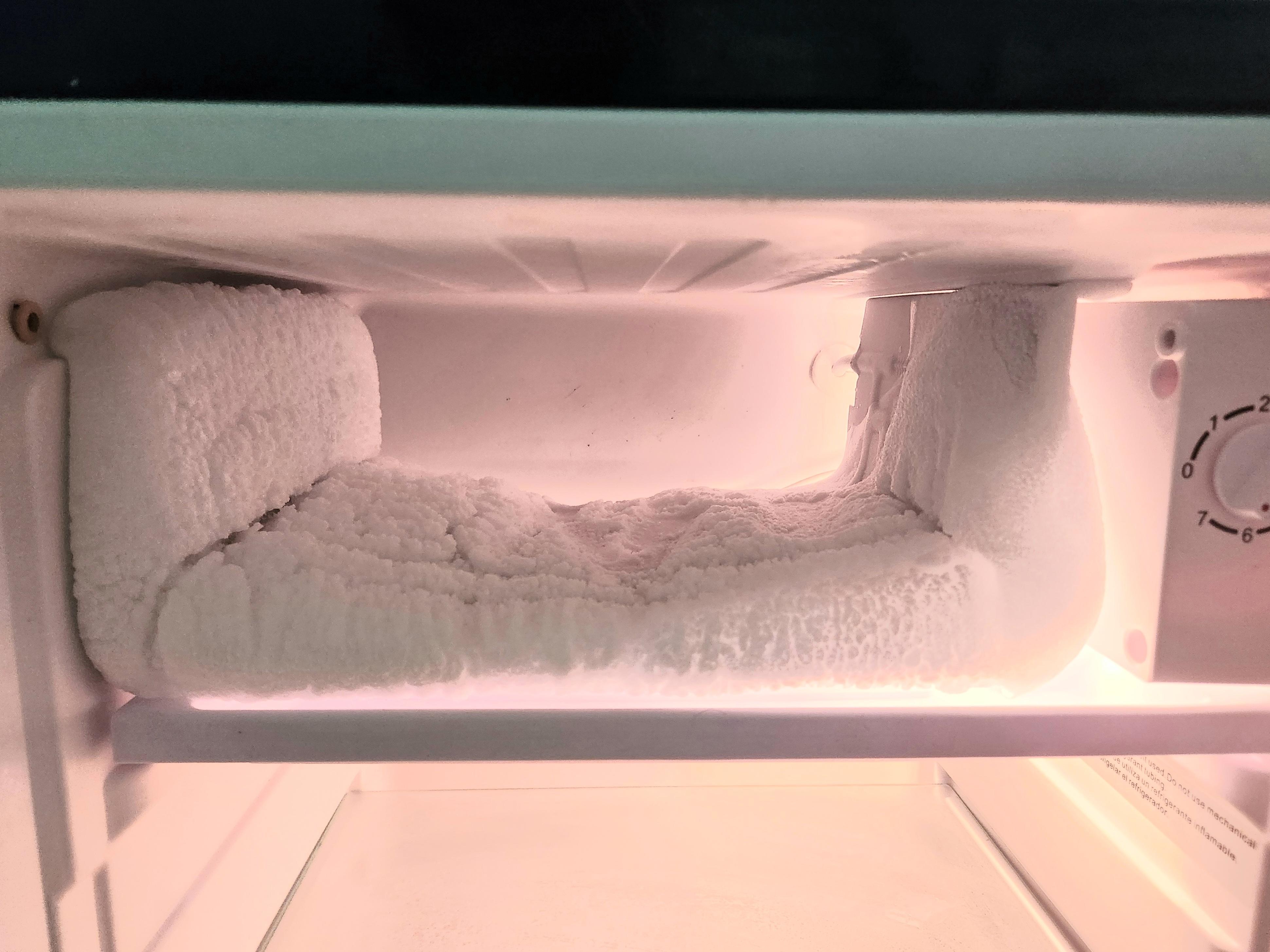 Freezer in mini-fridge, layers of 'snow' & no door on freezer.