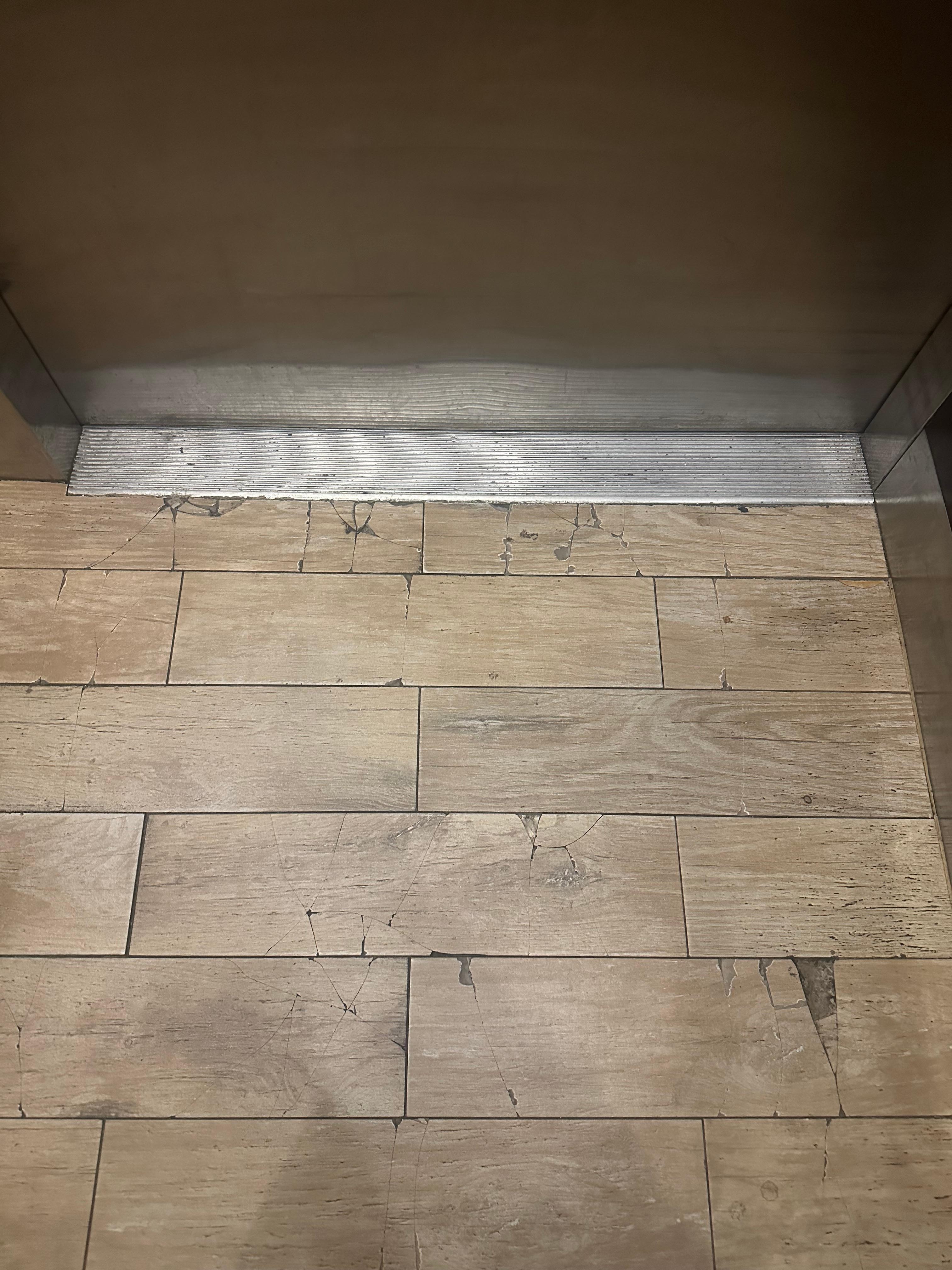 Tiles in elevator cracked and chipped, and threshold dirty