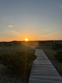 The sunrise peeking over the dunes on the path toward the beach.