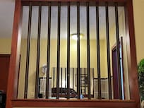 Metal bars separate the bathroom area from the bedroom.