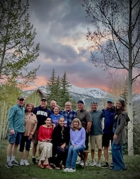 Group Photo in front of house with Breckinridge Ski Resort and sunset in the background.