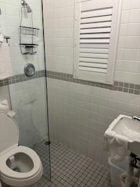 To shower, one needs to reach around this partial plastic(?) barrier and adjust the shower without getting soaked with cold water which floods the floor right up to the sink.