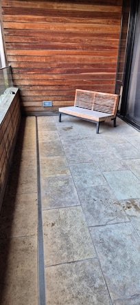 Outdoor balcony space but no outdoor furniture besides 1 old wooden bench with no cushions.