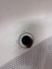 Rust encrusted drain in the bath