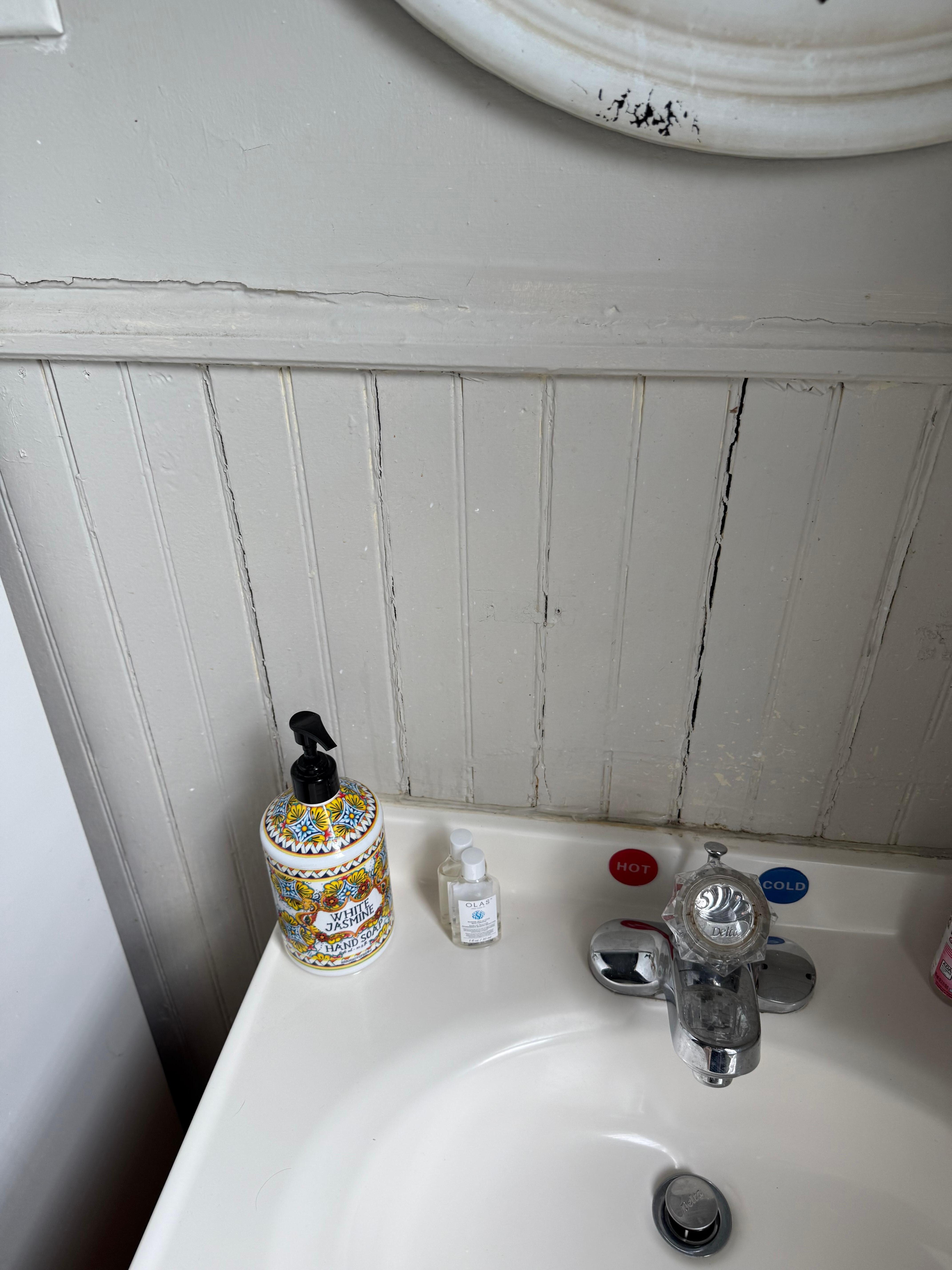 Wainscoting with major cracks throughout the bathroom 