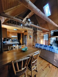 Views of kitchen, dining room, and livingroom. Loft stairs are pictured off of living room.