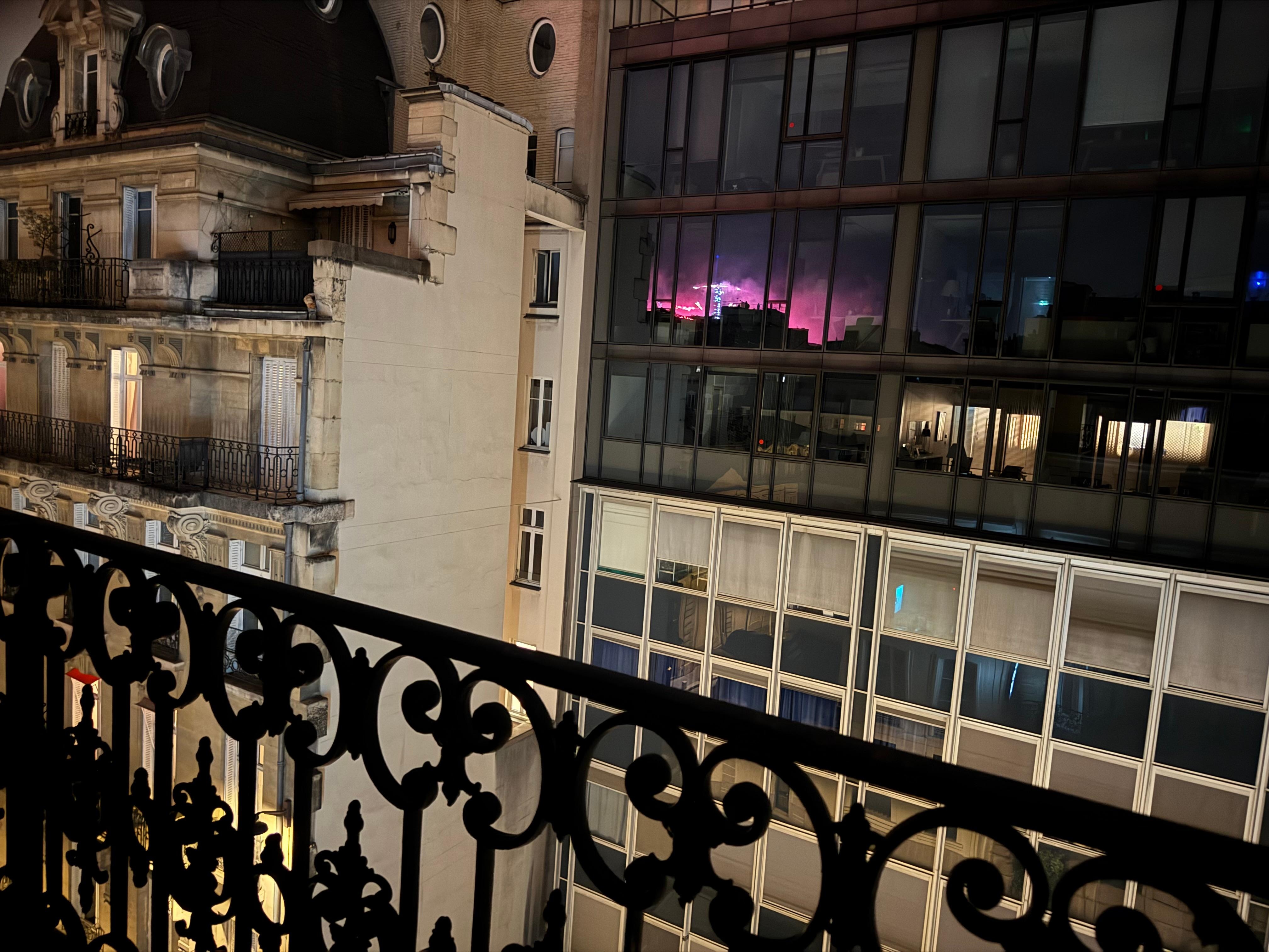 Reflection of fireworks around Eiffel Tower taken from balcony.