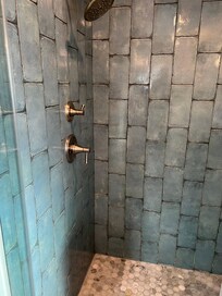 Beautifully tiled shower with wall and rain shower heads.