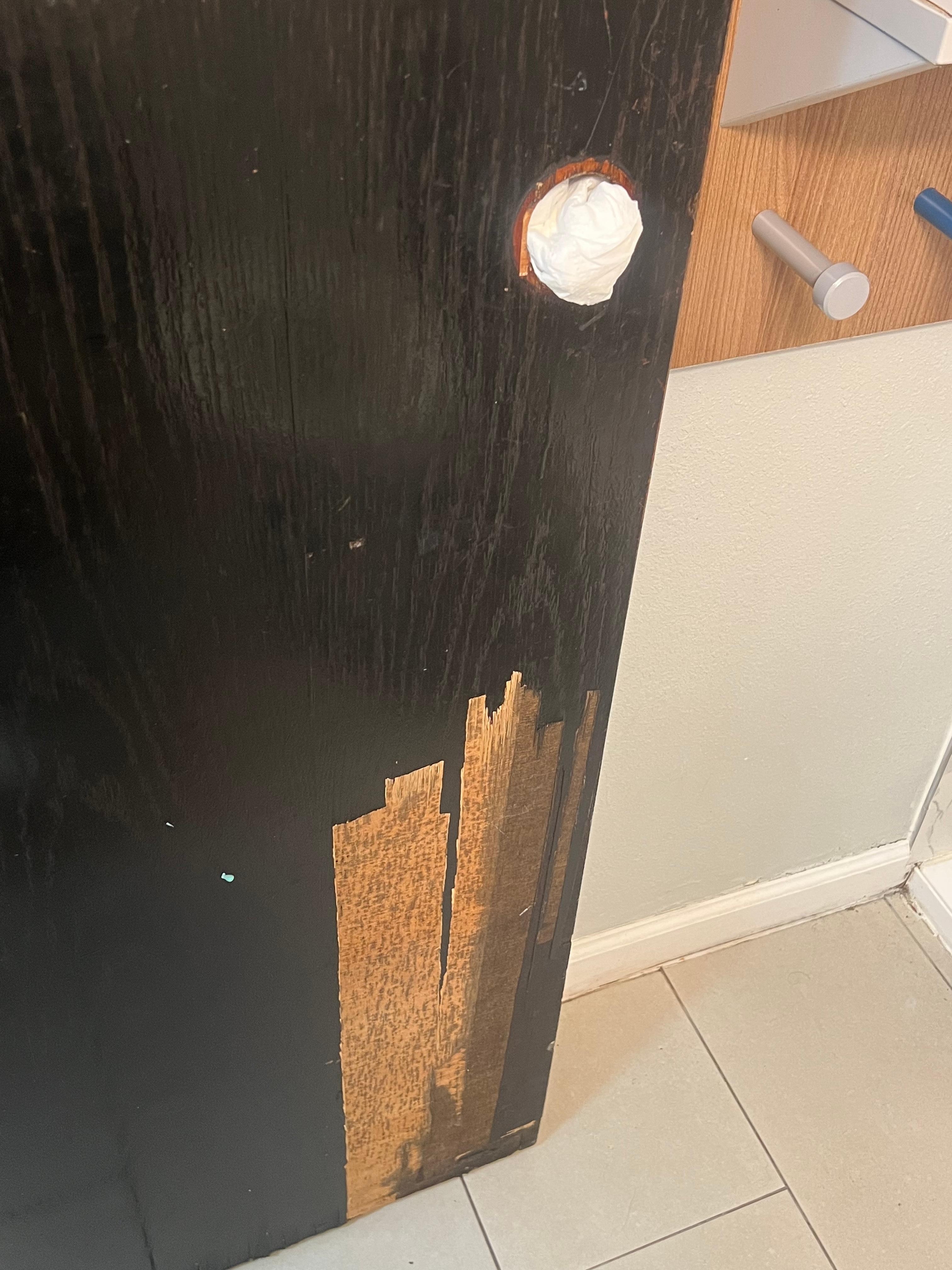 Broken doorknob with paper towels filled in the middle. Also, the door is broken.
