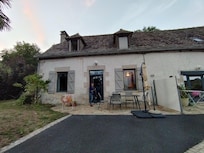 Terrasse avec mobilier d'extérieur et grand parasol devant l'entrée