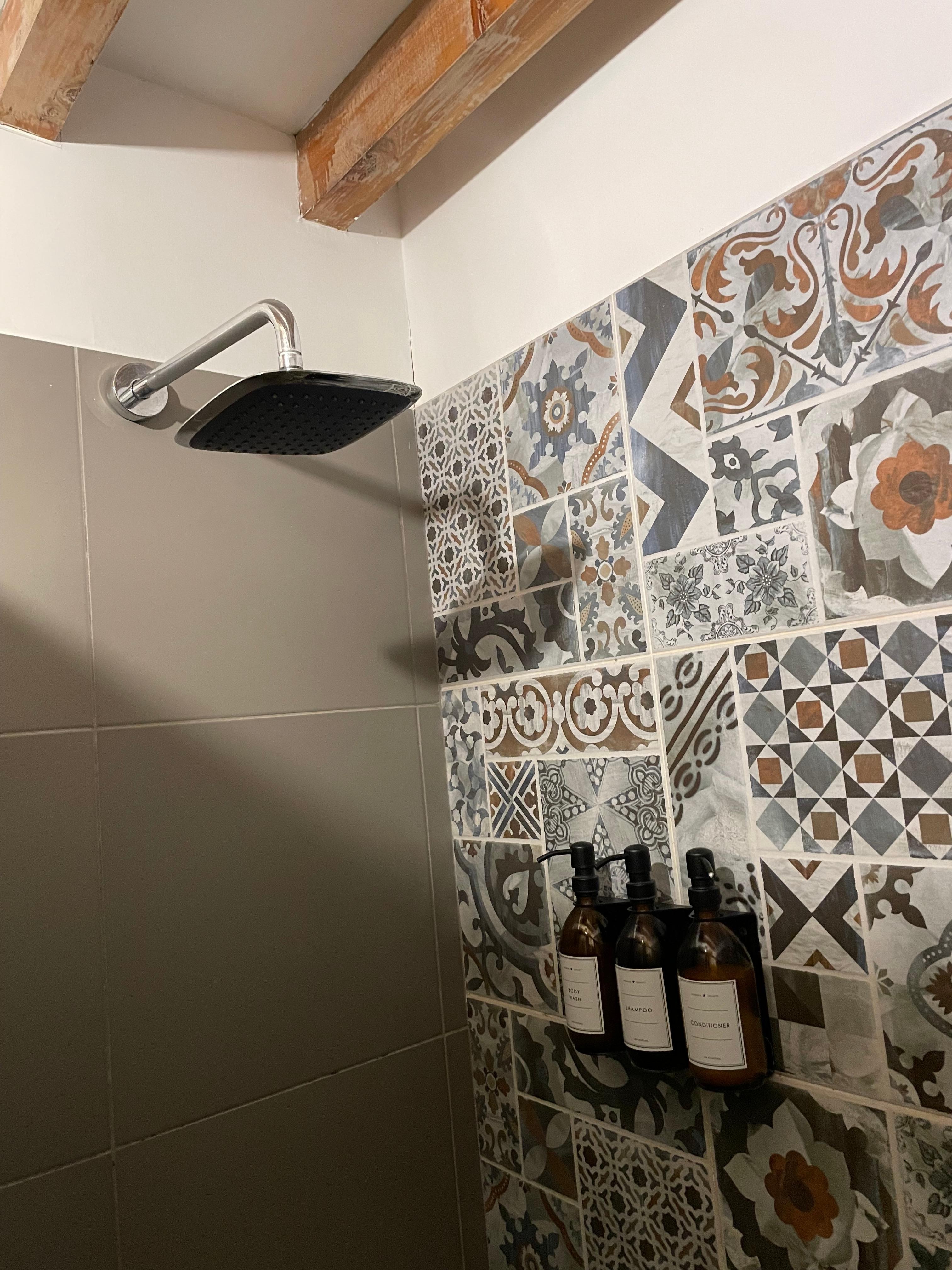 Full shower head and nicely tiled walls. 