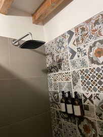Full shower head and nicely tiled walls.
