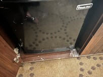 Milk/ice cream all over the outside of the mini fridge and cabinet
