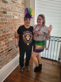 Standing behind the table in the open living space preparing to attend the first parade of the 2026 Mardi Gras Season