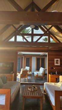View from the kitchen with the indoor living room in the foreground, the outdoor sitting room in the midground, and the door to the master bedroom suite in the background.