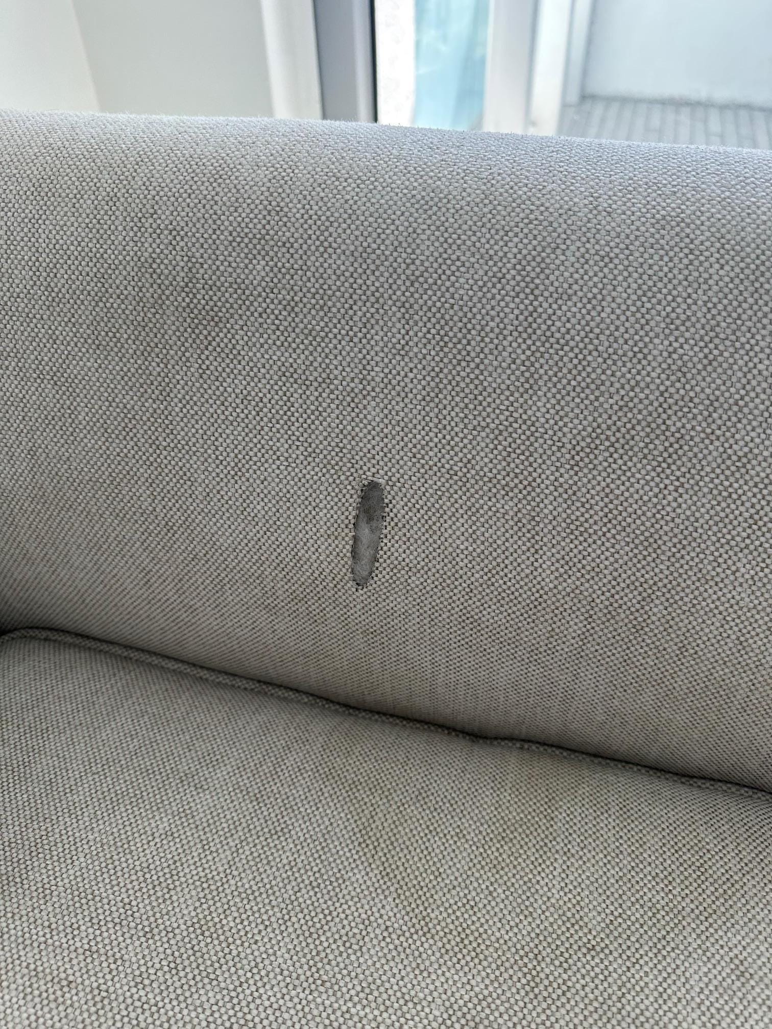 Dirty stained couch with a burn hole in it