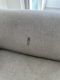 Dirty stained couch with a burn hole in it