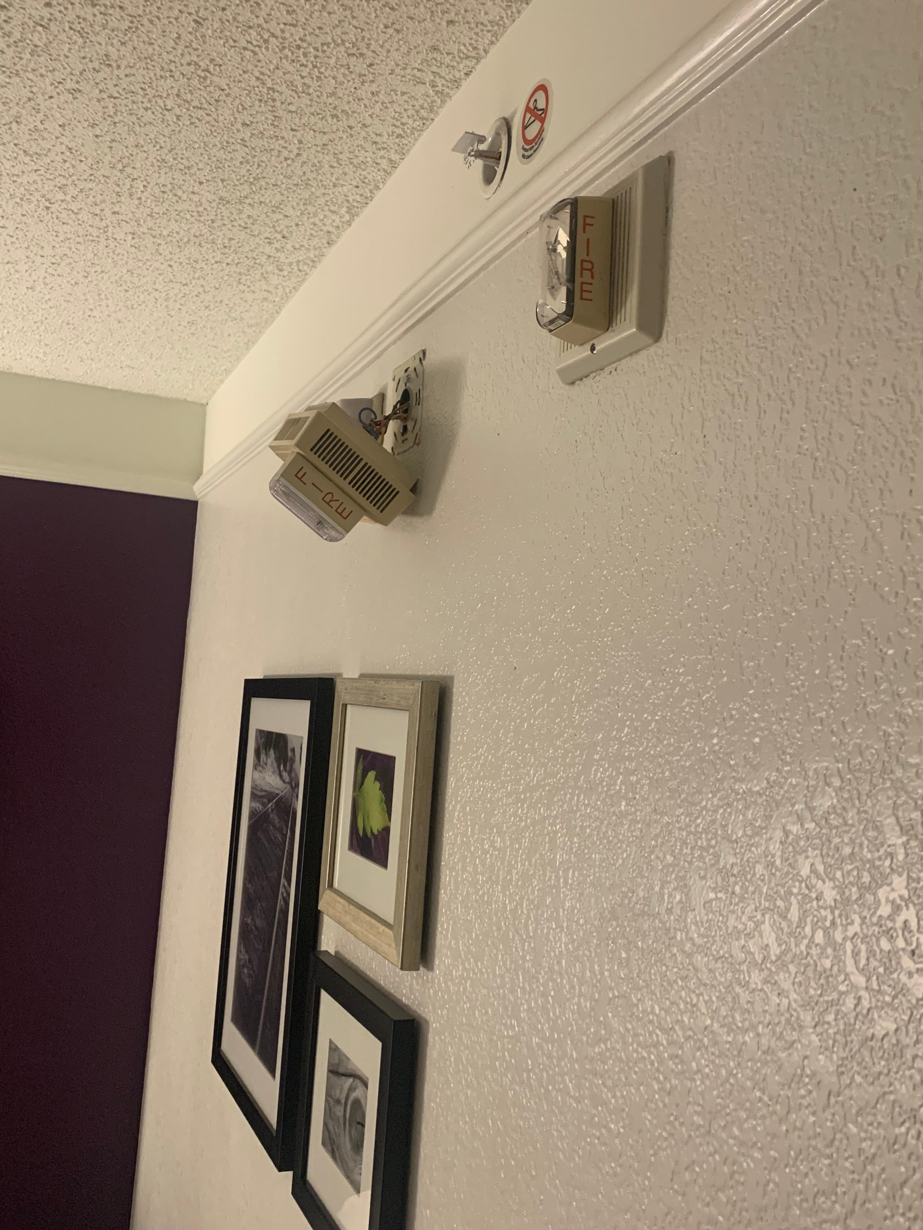 Fire alarm hanging off wall by its wires