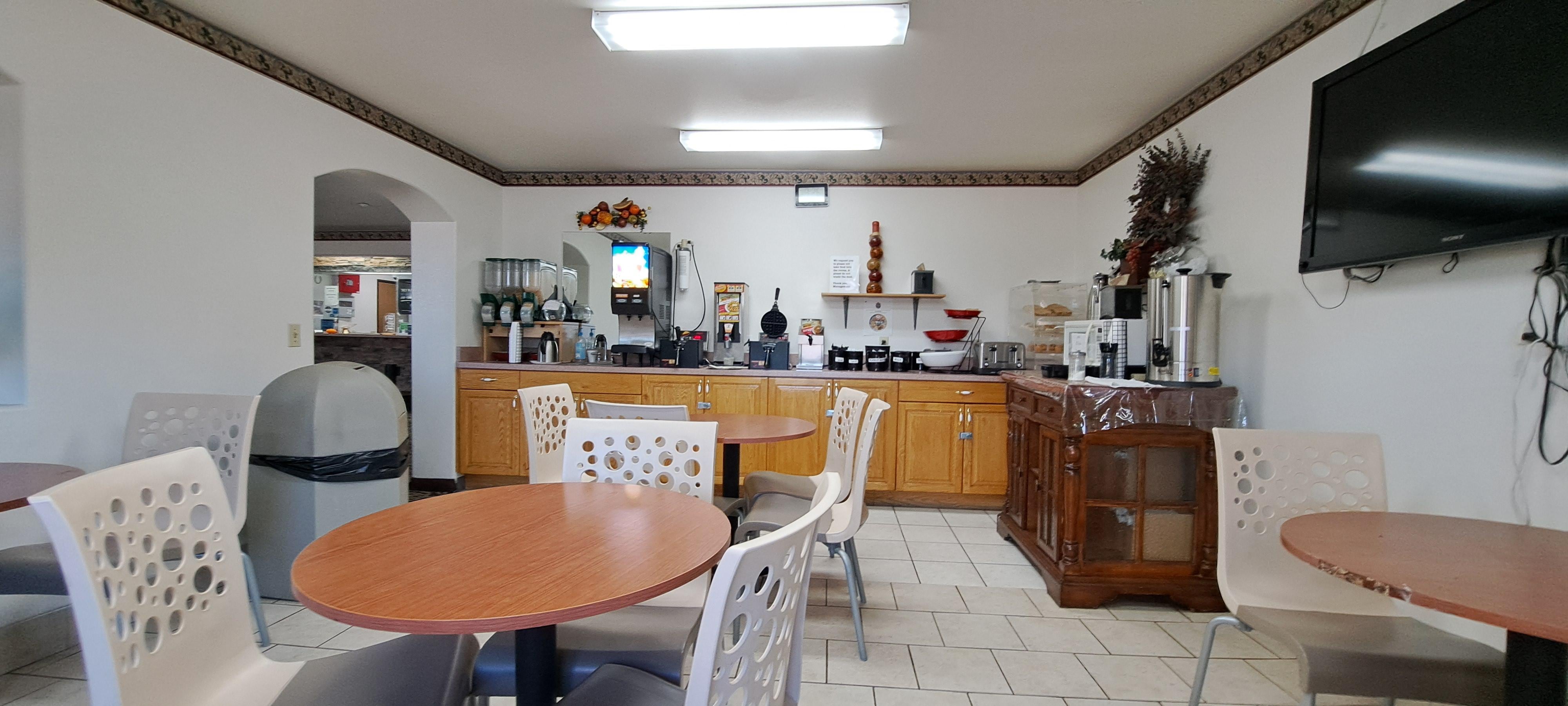 Dining area with plenty of breakfast options: dry cereal, waffles, bread, English muffin and regular muffin, orange juice and apple juice.