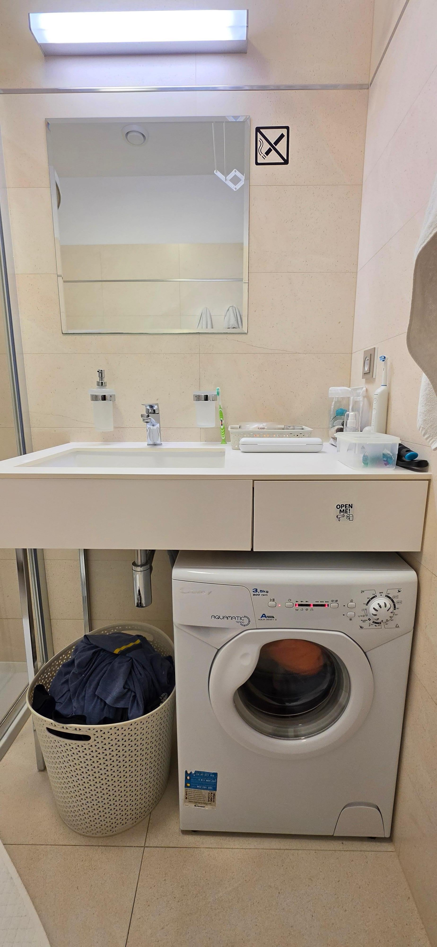 Small washing machine and drying rack in bathroom. 
