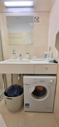 Small washing machine and drying rack in bathroom.
