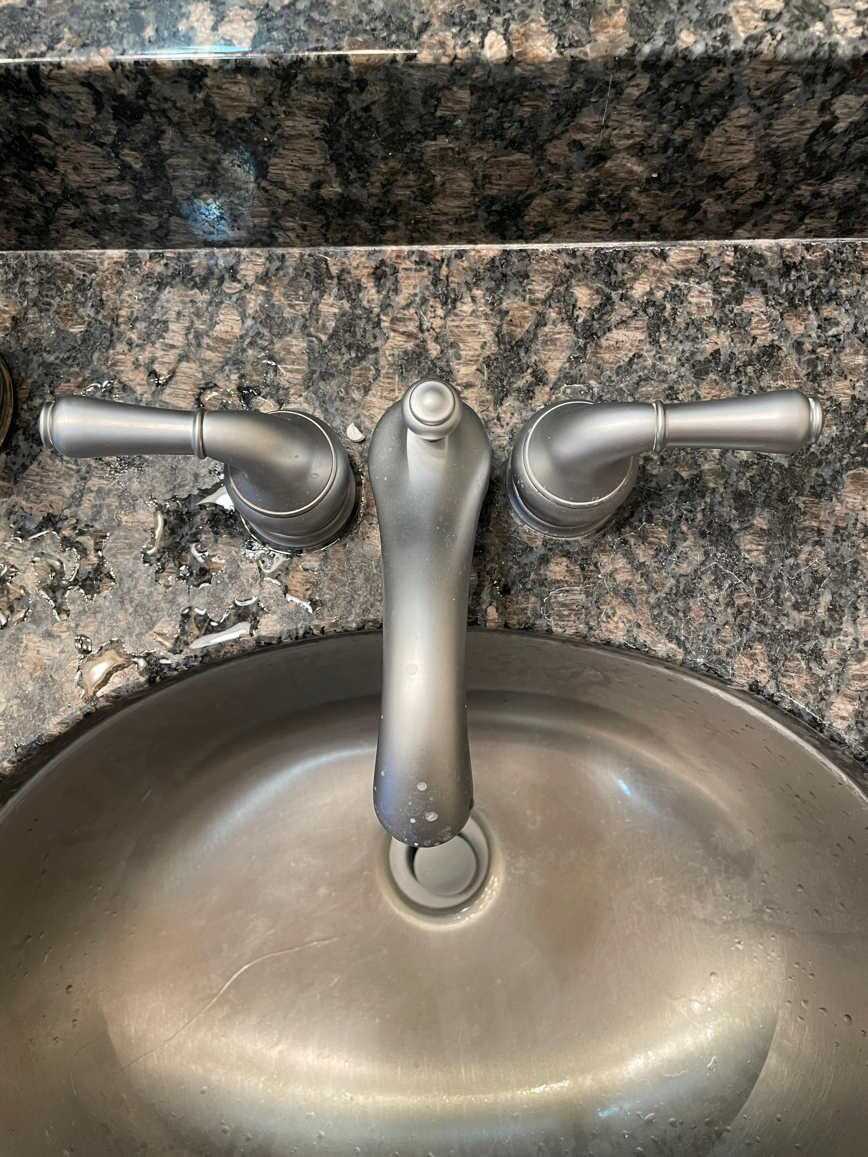 Dirty sink with a half of a pill on the counter 