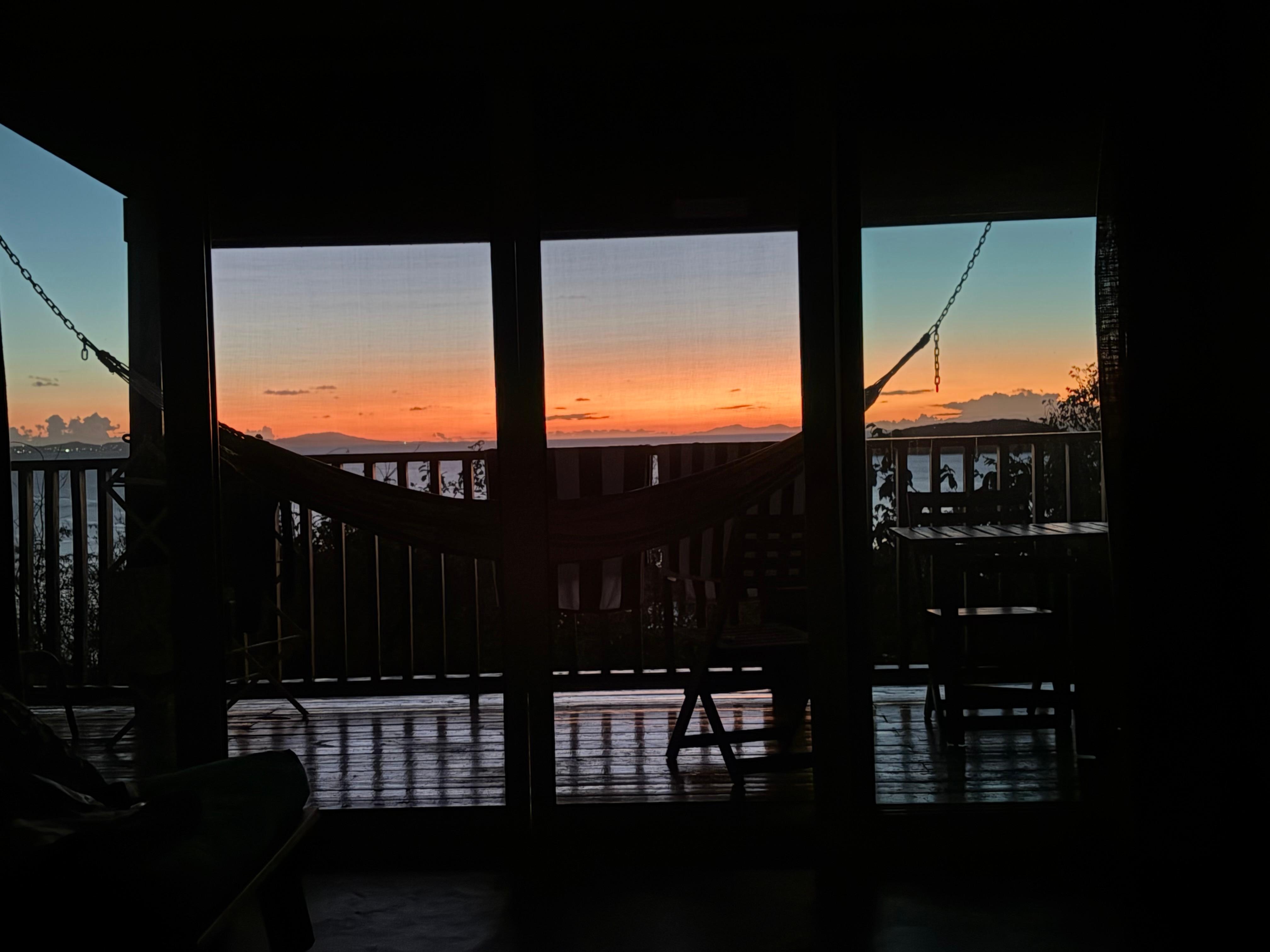 Sunset from the bed, looking out through the screen doors and hammock. 