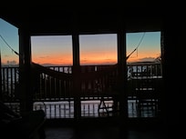 Sunset from the bed, looking out through the screen doors and hammock.
