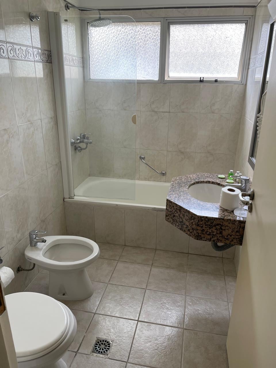 Banheiro velho. A água vaza pelo box e inunda a chão do banheiro