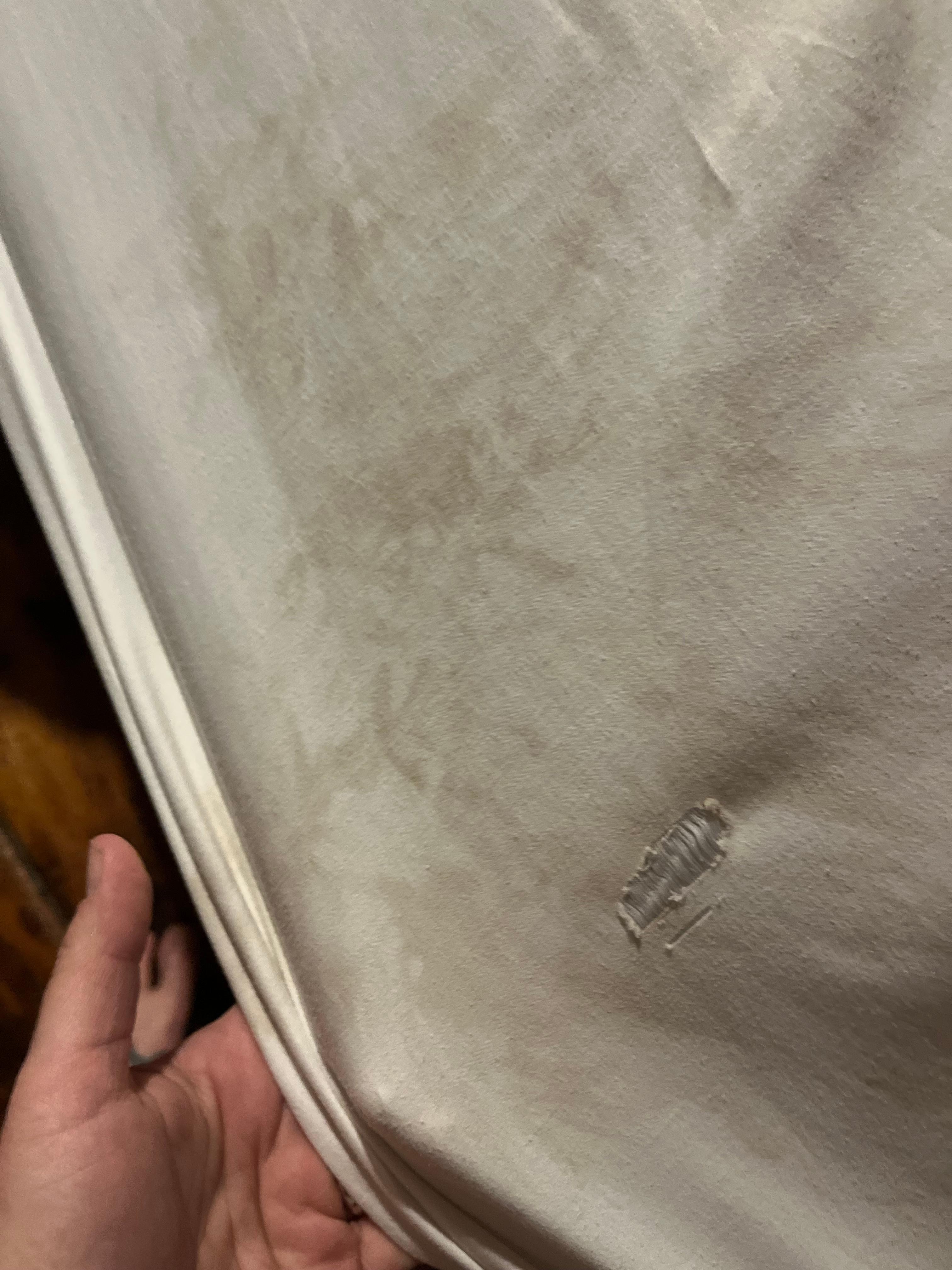 Fitted sheet with holes and stains.
