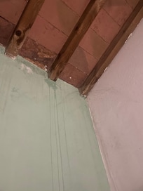 Clear water damage at ceiling water streaming down wall.