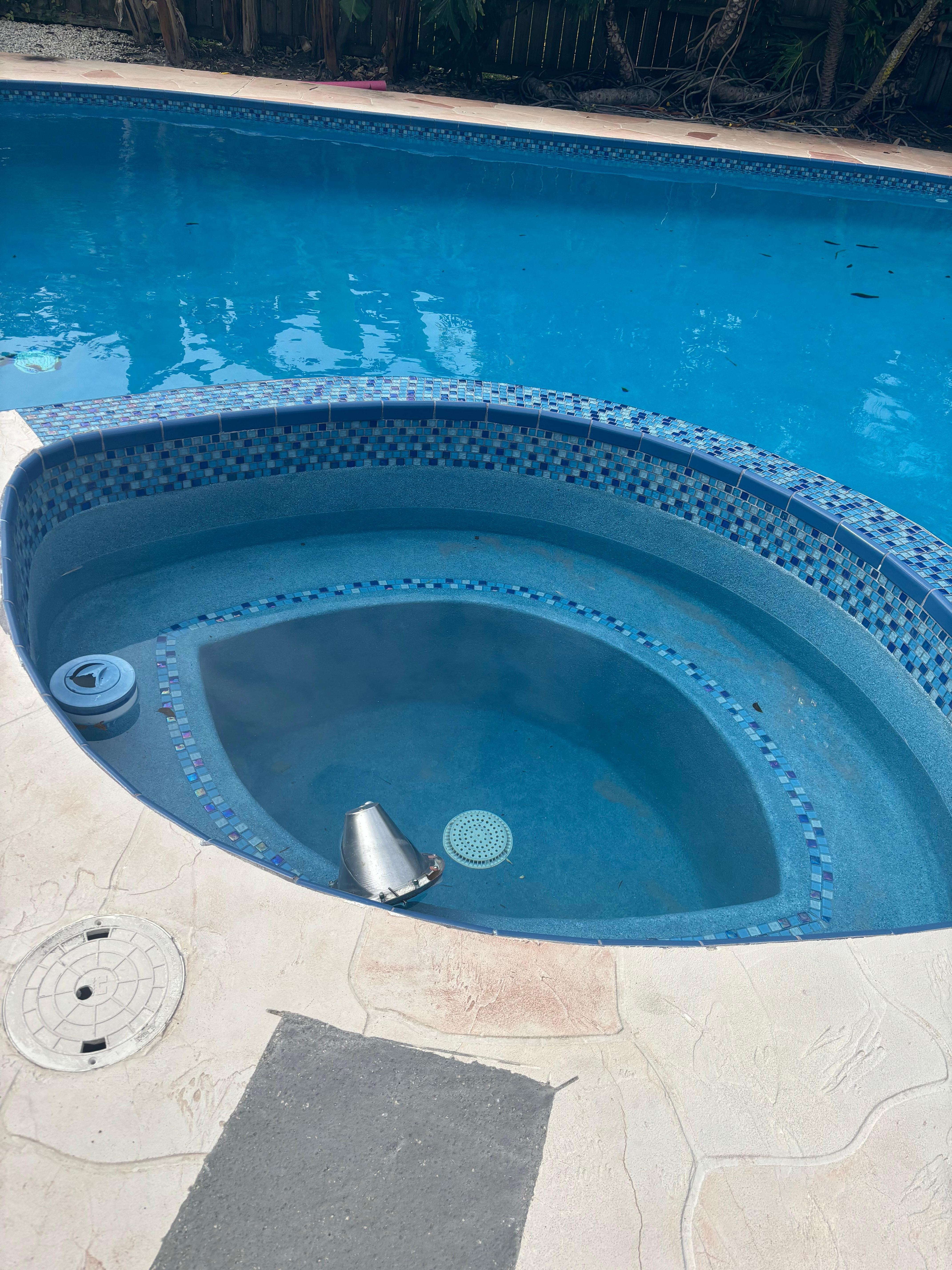 Hot tub half empty, light connected by wire floating in the water 