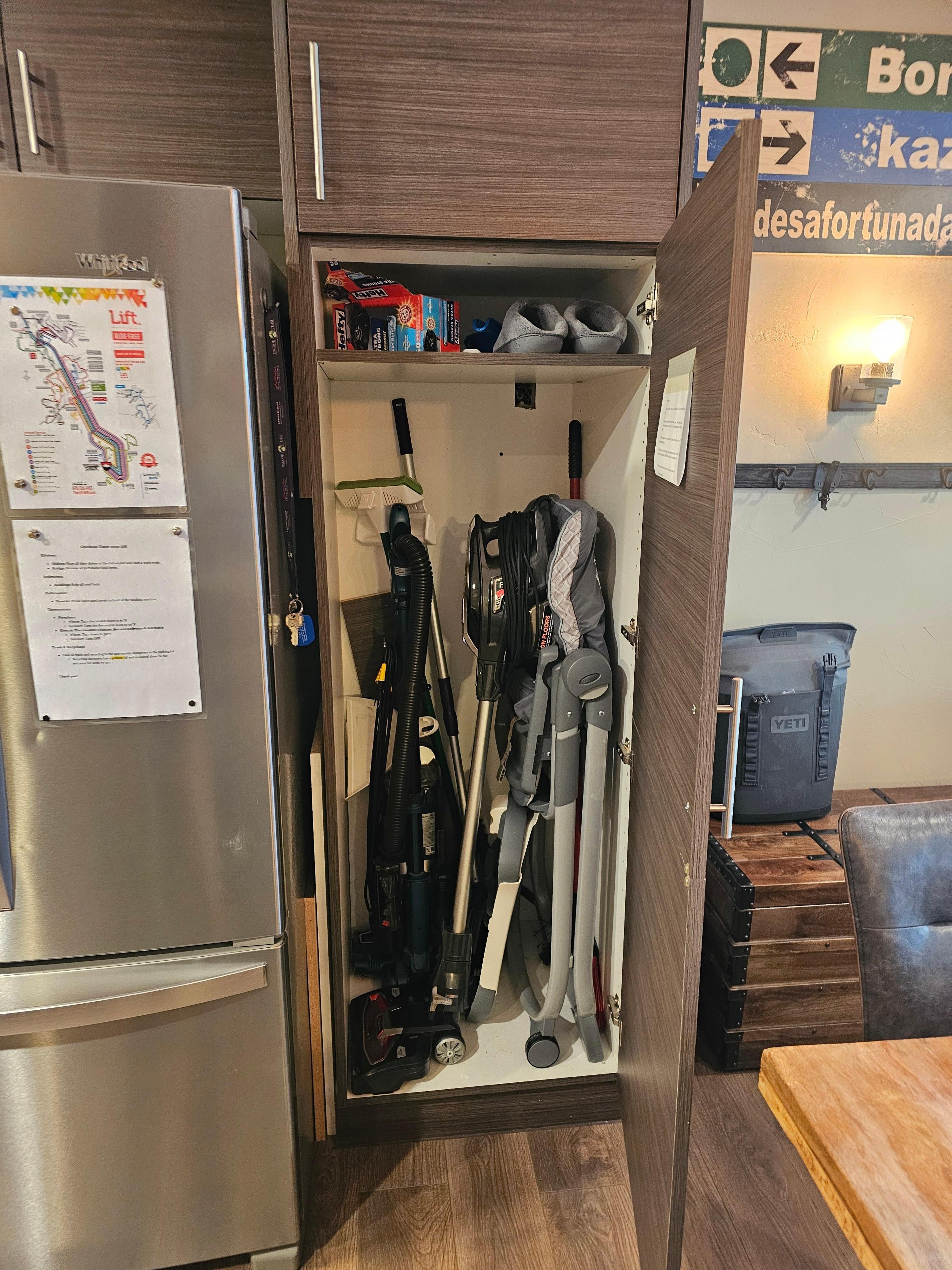 Second largest storage space filled with cleaning supplies and a high chair.