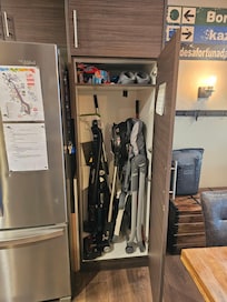 Second largest storage space filled with cleaning supplies and a high chair.