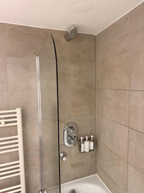 Shower head is too close to wall to comfortably rinse off. The shower door swings open and the floor becomes drenched.