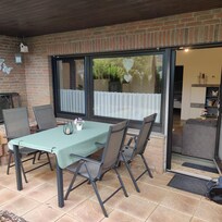 Terrasse mit Sichtschutz zur Anliegerstraße.
Tisch, Stühle mit Auflagen, Liegestühle, Sonnenschirm, Grill.
Sonne und Schatten.