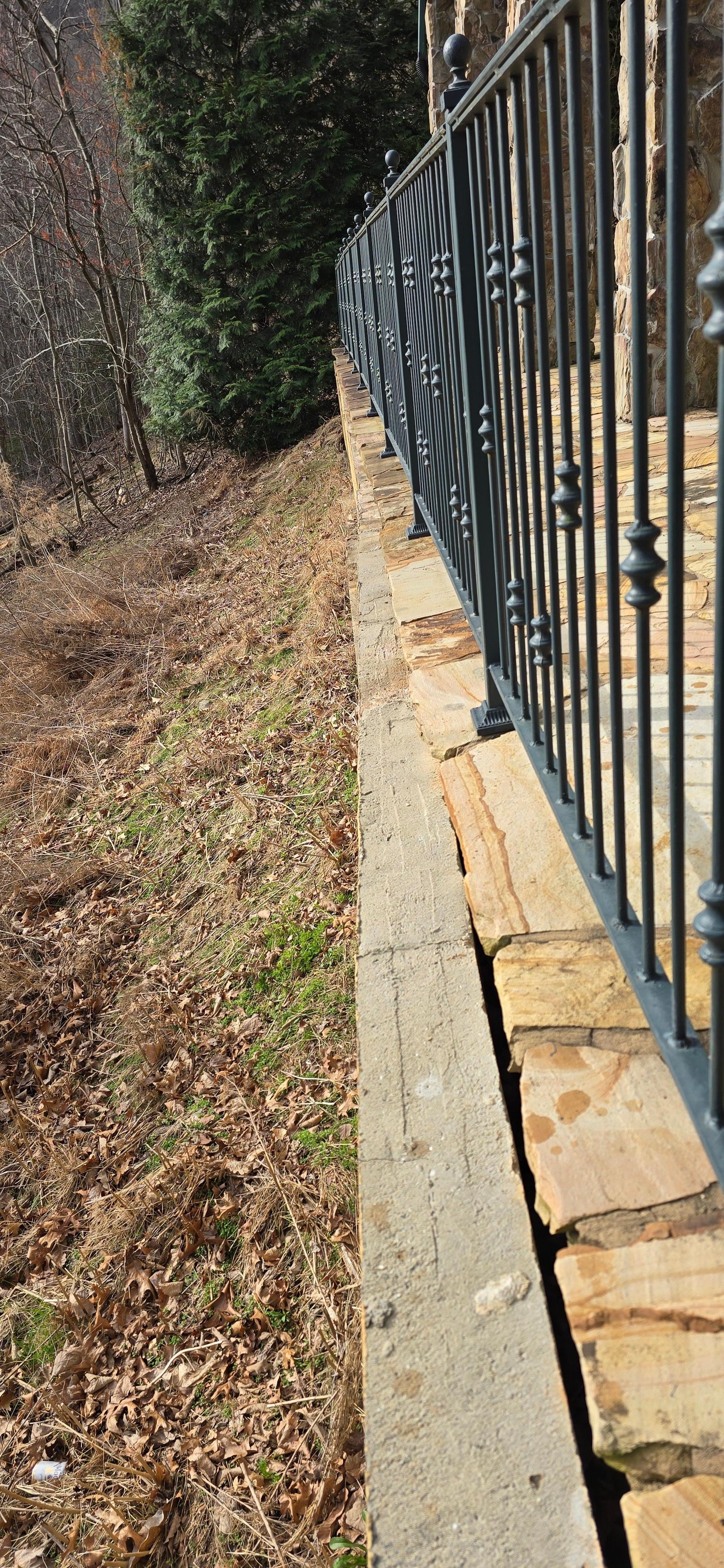 Picture shows the retaining wall slowly coming out from the patio. The patio is no longer supported. House supports rest on the patio also. No structural support.