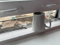 Broken window held open with a coffee mug.