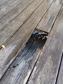 Close up of large hole in decking - dangerous!