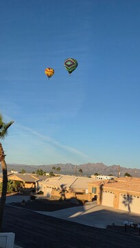 More beautiful hot air balloons over the neighborhood with the mountains in the background.