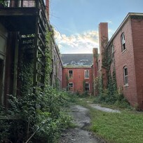 Several dilapidated buildings to the immediate sides with broken roofs and windows with ample graffitti