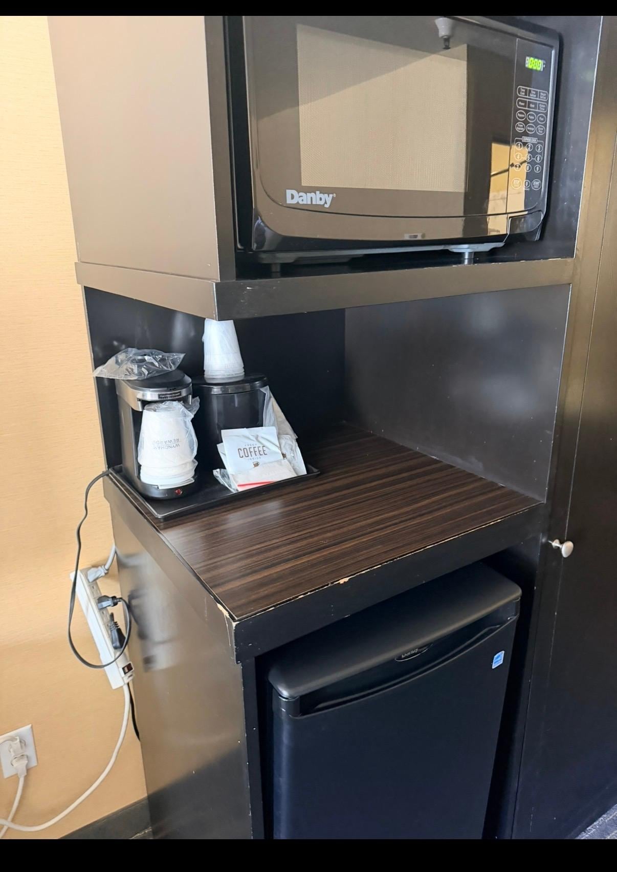 Coffee station. Sadly, the edges of most of the furniture looked like this. The power cords to the coffee maker, microwave, and refrigerator are all plugged into the exposed and dangling power strip.
