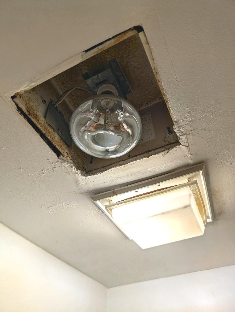 Uncovered heat lamp and non-working ventilator fan in bathroom
