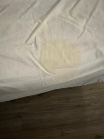 large yellow stain at foot of the bed on sheets
