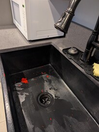 This is chipping paint. The sink was originally red so to make it look better for listing pictures, it and the faucet was painted black.