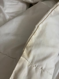 Yellowed white comforter in guest bedroom right bed.