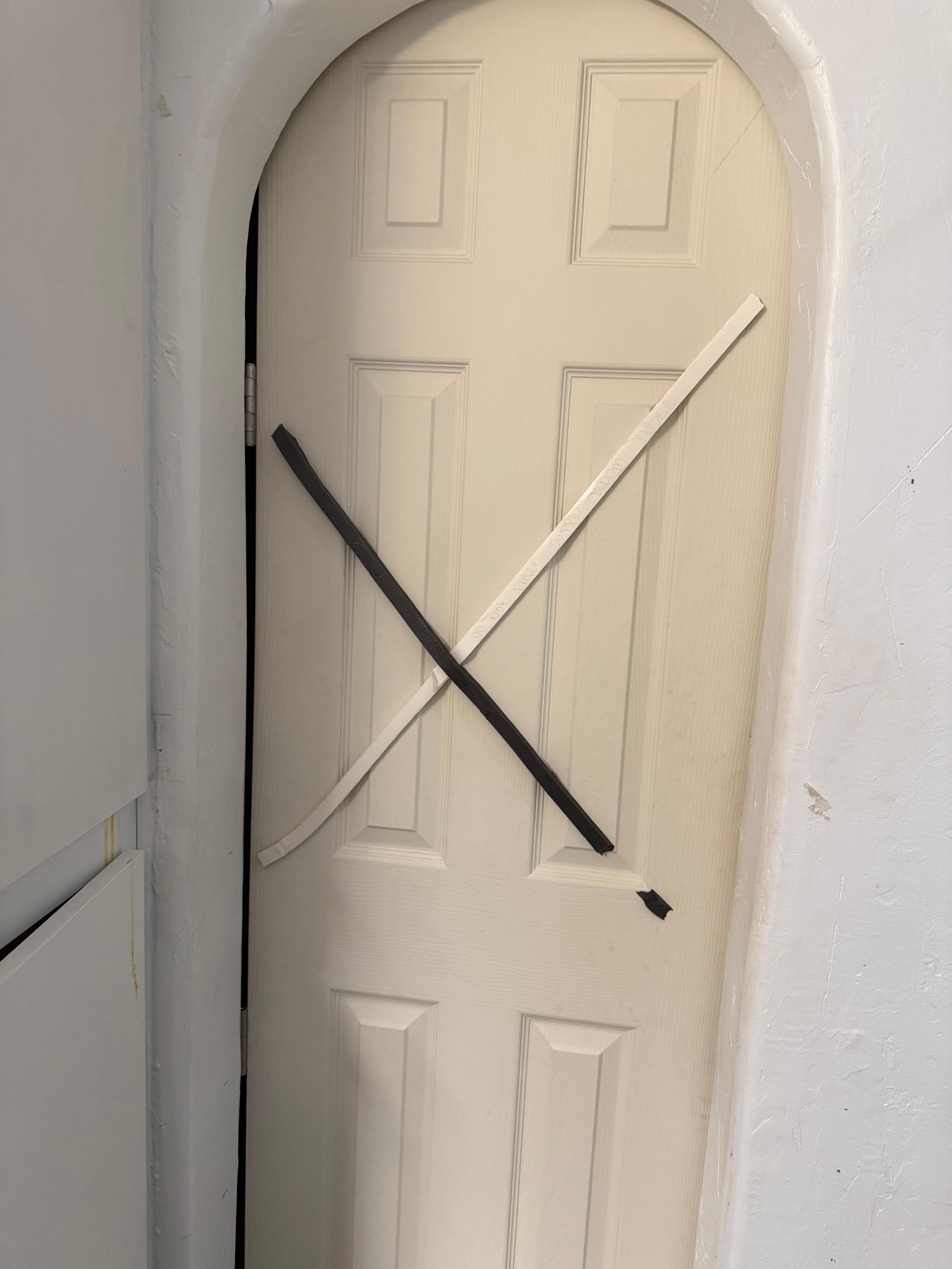 A whole door closed off with mounting tape and hand writing 