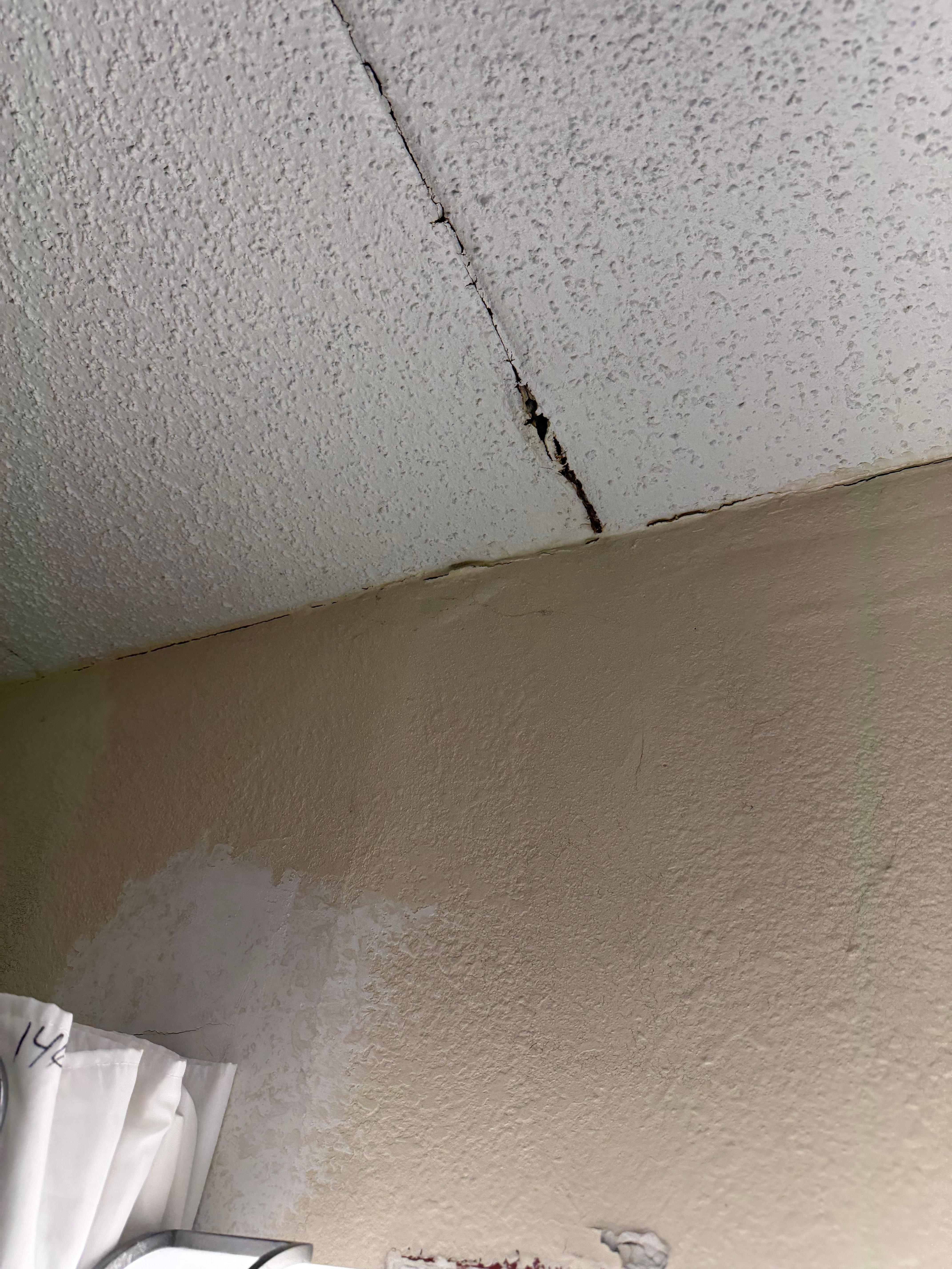 One of multiple cracks in ceiling and several unpainted wall where it was patched