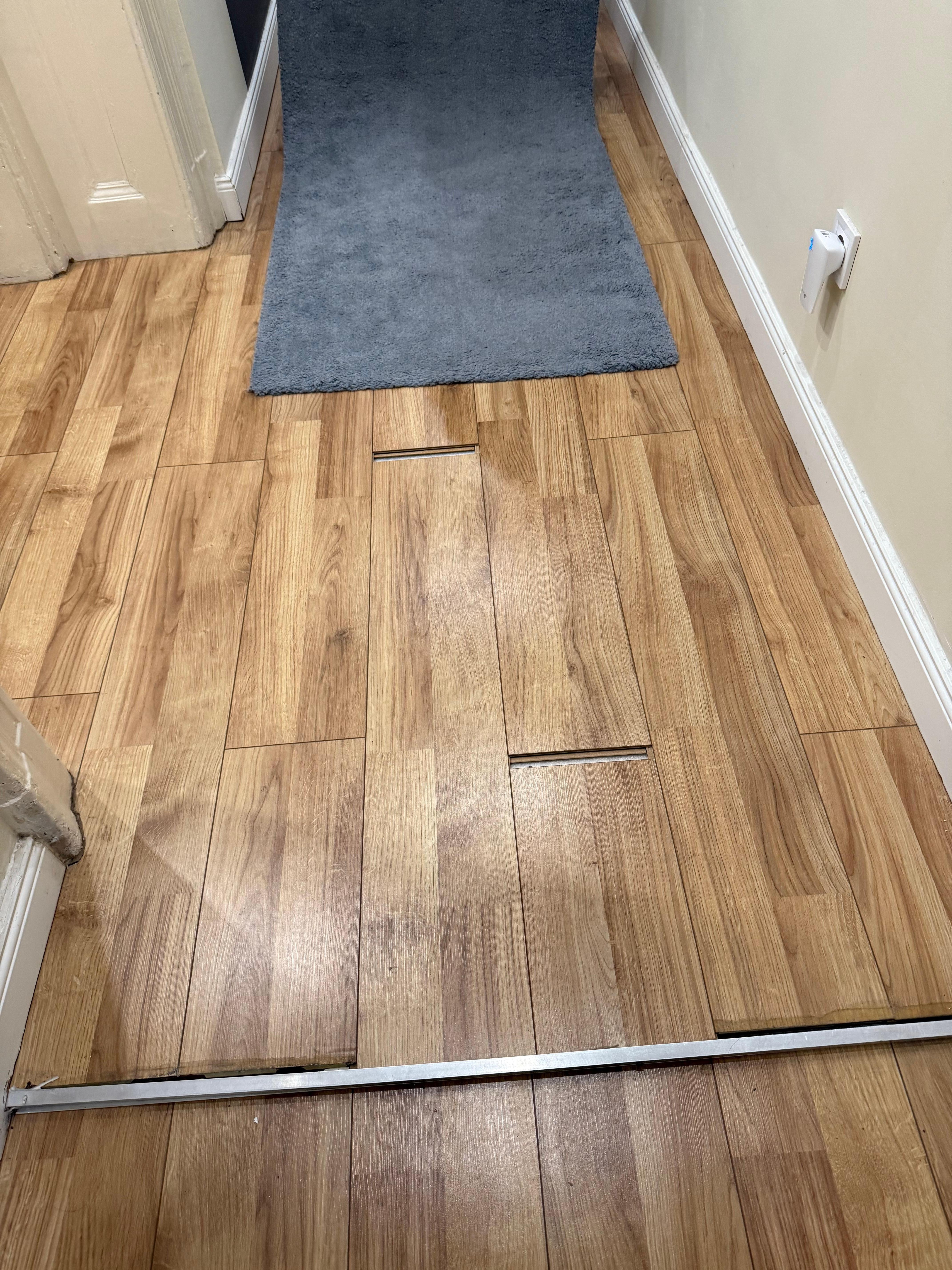 Holes in wood flooring covered by a rug making us trip