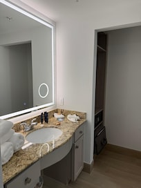 This is the bathroom sink. It has a nice lit mirror. It has an area in the mirror that is actually magnified.